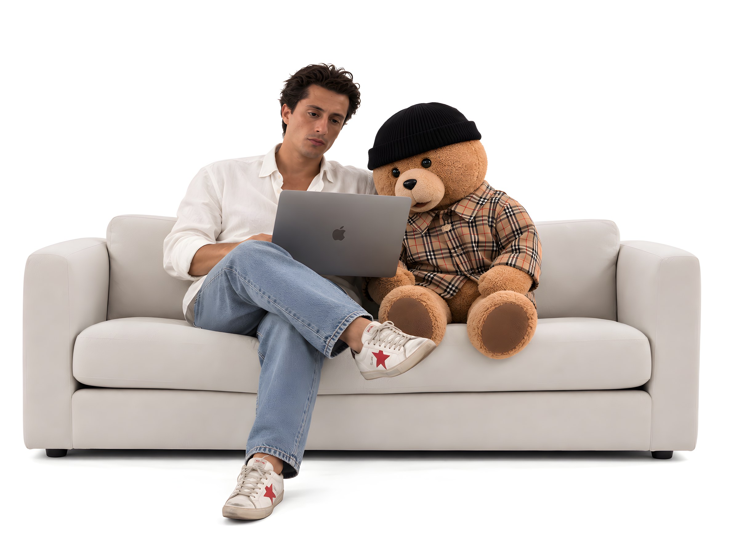 Homem sentado num sofá a trabalhar no portátil, com um urso de peluche de gorro a espreitar o ecrã